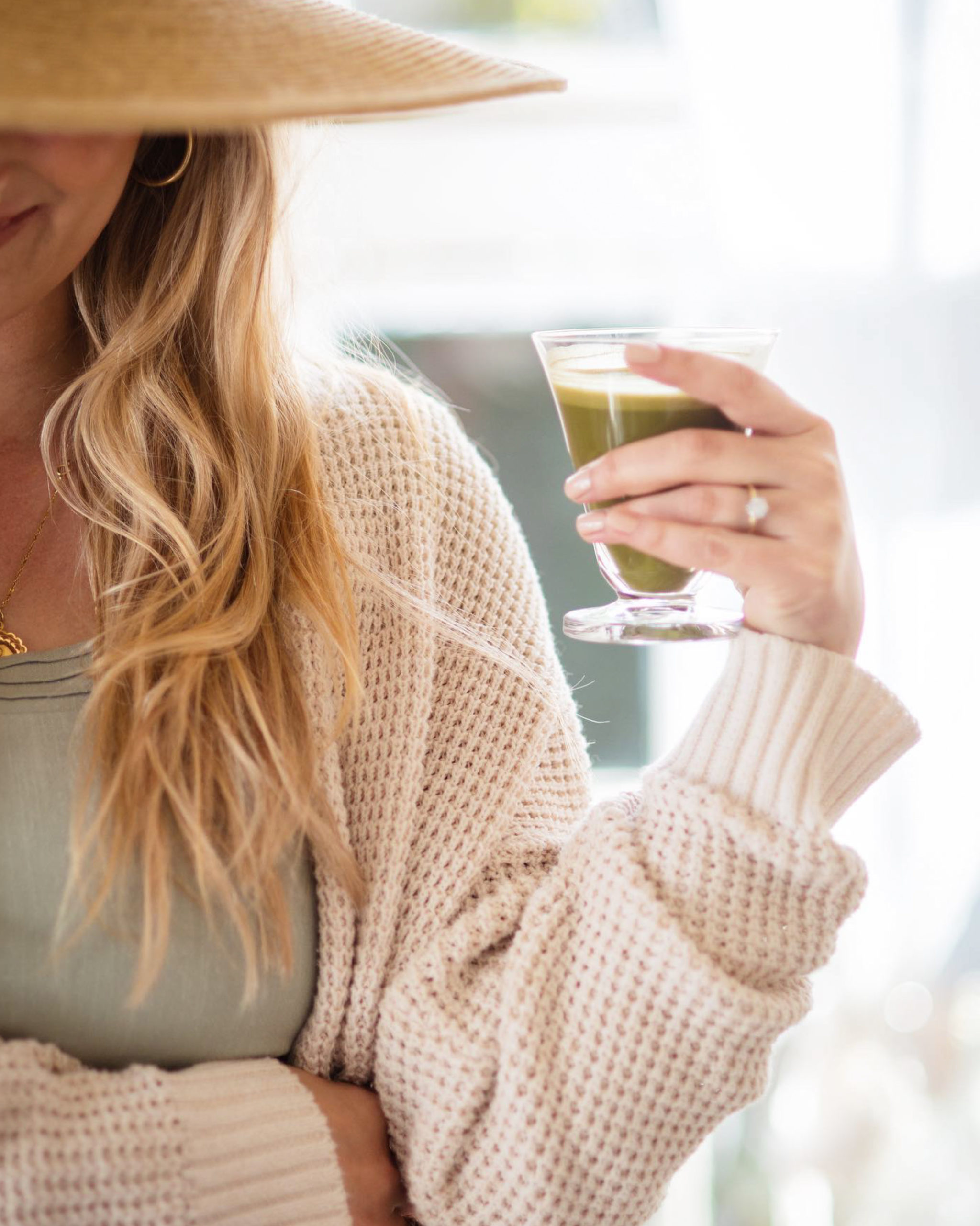 Alt text: "Smiling woman holding a green smoothie, looking refreshed and rejuvenated. She may have just used one of the 7 ways to quickly get out of a creative rut featured in the blog post by Virtual Career Girl
